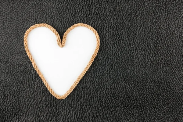 Symbolic heart made of rope lying on a natural leather — Stock Photo, Image