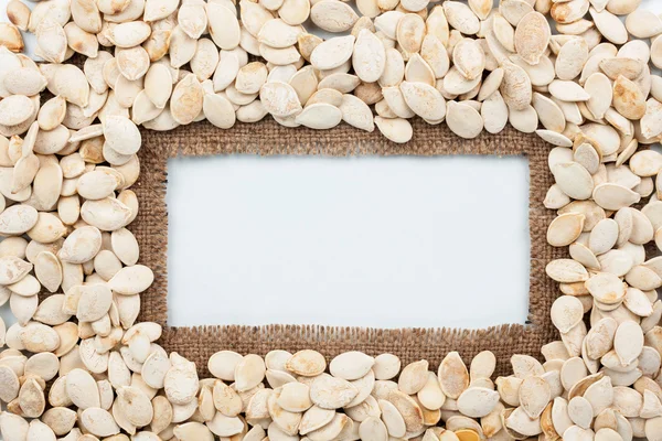 Telaio fatto di iuta e semi di zucca si trova su sfondo bianco — Foto Stock