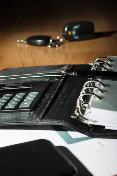 Surface of a wooden table with a notebook, smart-phone, car keys — Stock Photo, Image