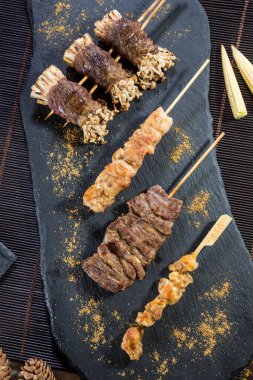 Biftek, tavuk ve baharatlı baharatlı ve süslenmiş enoki mantarlı ızgara şiş..