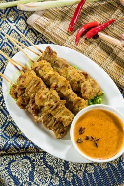 Kızarmış satay şişleri, marul ve fıstık sosuyla servis edilir, kırmızı biber ve yıldız anason ile süslenir..