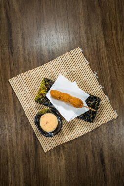 Süslü tabakta kremalı acı biber sosuyla servis edilen kızarmış şiş ve bambu hasırı..