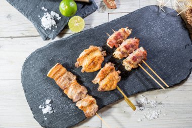 Lezzet ve sunum için limon parçaları ve kaba tuz kristalleriyle süslenmiş beş ızgara et şişi..