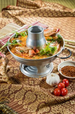 Tayland usulü Tom Yum güveç tenceresi, karides, mantar ve bitkilerle, kültürel malzemeler ve malzemelerle şekillendirilmiş..