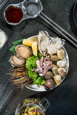 İstiridye, istiridye, istiridye, istiridye, karides ve marul ve limonla süslenmiş mürekkep balığı içeren çeşitli çiğ deniz ürünleri..