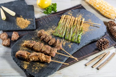 Mısır, limon, maydanoz ve köy dekoruyla servis edilen ızgara et ve sebze şişleri..