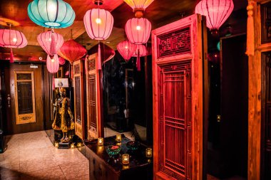 Renkli fenerler, oyulmuş ahşap, altın bir heykel ve mum ışığında sıcak bir atmosferi olan Asya tarzı bir iç mekan..