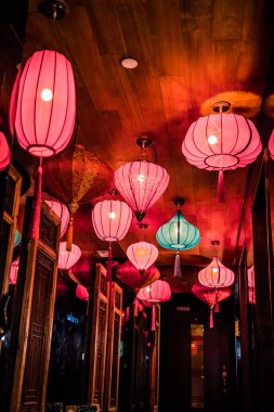 Ahşap bir tavandan sarkan renkli Asya fenerleriyle dolu bir koridor. Aynalar ve sıcak aydınlatmayla..