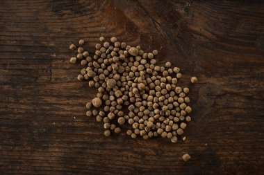 Koyu ahşap üzerine dağılmış yuvarlak kahverengi topaklar, muhtemelen hayvan yemi ya da evcil hayvan maması..