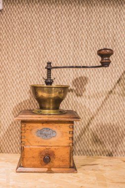 Geleneksel bir kahve öğütücüsü, ahşap tabanı, pirinç kasesi, el kolu, gösterişli klasik mutfak işçiliği ve dokunsal tasarımı..