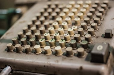 0 'dan 4' e kadar etiketlenmiş yuvarlak plastik tuşlu eski bir mekanik toplama makinesinin yakın çekimi, metalik bir cisim üzerinde aşınma ve renk bozulması belirtileri gösteriyor.