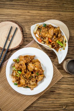 Kızarmış domuz eti, yeşil soğan, havuç ve baharatlı sos. Kırsal ahşap bir masada iki tabakta servis ediliyor..