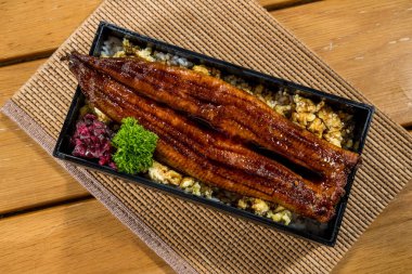 Japon bento kutusu, ızgara yılan balığıyla pilav ve çırpılmış yumurta, turşu ve maydanozla servis ediliyor..