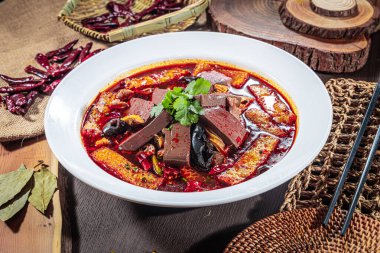 Ördek kanı, tofu derisi, mantar ve biber yağı çorbasından oluşan kişniş soslu ve baharatlarla çevrili cesur bir Sichuan usulü güveç..