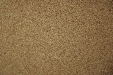 Sıkıca paketlenmiş tıpa parçacıklarını gösteren bir mantar pano yüzeyinin yakın görüntüsü, genellikle notları veya duyuruları iğnelemek için kullanılır.