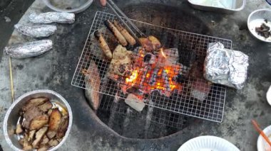 Gün batımında açık gökyüzünün altında, kamp ateşinin yanında leziz ızgaralar.