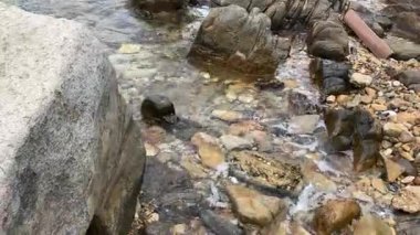 Gün batımında kayalık bir sahilin dingin güzelliğini keşfediyorum. Nazik dalgalar taşlara çarpıyor.