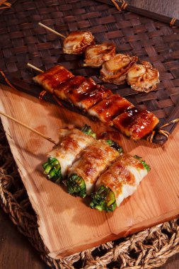 Üç şişe deniz tarağı, jöleli yılan balığı ve ete sarılmış sebzeler benekli siyah bir tabakta servis ediliyor..