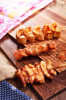 Üç Japon stili şiş, iki tavuk eti ve baharatlı soya peyniri ya da soya peyniri ve çuval bezi kumaşlı bir tahta üzerinde servis edilen yüksek kaliteli bir stok fotoğrafı.