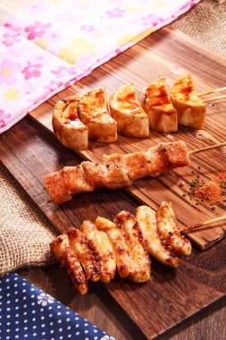 Üç Japon stili şiş, iki tavuk eti ve baharatlı soya peyniri ya da soya peyniri ve çuval bezi kumaşlı bir tahta üzerinde servis edilen yüksek kaliteli bir stok fotoğrafı.