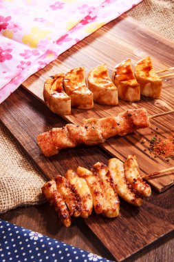 Üç Japon stili şiş, iki tavuk eti ve baharatlı soya peyniri ya da soya peyniri ve çuval bezi kumaşlı bir tahta üzerinde servis edilen yüksek kaliteli bir stok fotoğrafı.