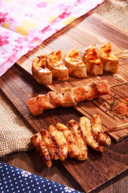 Üç Japon stili şiş, iki tavuk eti ve baharatlı soya peyniri ya da soya peyniri ve çuval bezi kumaşlı bir tahta üzerinde servis edilen yüksek kaliteli bir stok fotoğrafı.