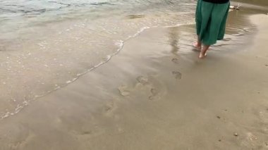 Gün batımında sahilde keyifli yürüyüşler. Yumuşak dalgalar kuma vuruyor.