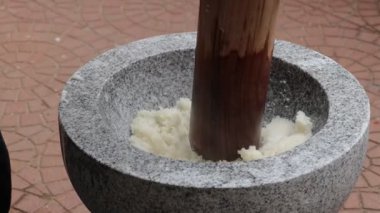 Parlak güneş ışığında geleneksel bir taş havan topuyla pirinç ezmek.