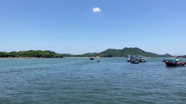 Sakin sular ve balıkçı tekneleri sakin bir kıyı manzarasında berrak gökyüzünün altında süzülüyor.