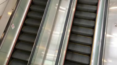 Hareketli bir alışveriş merkezinde yürüyen merdivenler hareketin ritmini ve sessiz anları gözler önüne seriyor.