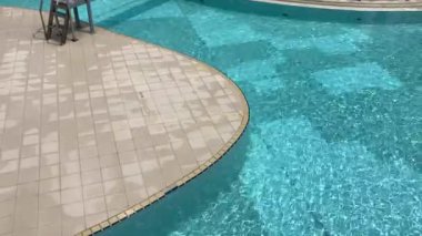 Güneşli bir öğleden sonra dinlenme tesisinde parlak yansımalar havuz yüzeyinde dans ediyor.