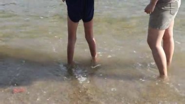 Güneşli bir öğleden sonra, çocukların kumsalda hafif dalgalarda yüzdüğü neşeli anlar.