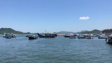 Gün ortasında sakin bir balıkçı köyünde açık mavi gökyüzünün altında kayıklar süzülüyor.