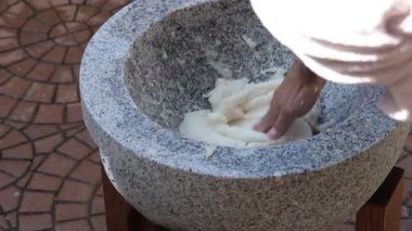 Güneşin altındaki taştan bir havan topunun içinde geleneksel hamuru elle yapmak.