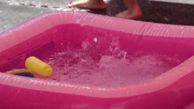 Güneşli bir öğleden sonra çocukların su oyuncaklarıyla oynadığı renkli bir havuzda yaz neşesi