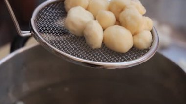 Canlı bir ev yemeği oturumunda mutfaktan tencereye yumuşak hamur topları.