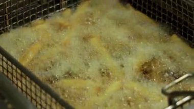 Canlı bir yemek oturumunda kızgın yağda kızaran çıtır altın patates kızartması.