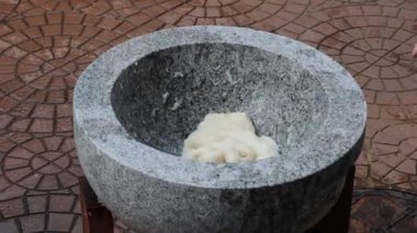 Tuhaf bir köyde canlı bir kültür festivali sırasında taş bir havanda hamur yapmanın geleneksel yöntemlerini keşfetmek.