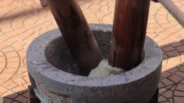 Güneşli bir açık havada tahta çubuklarla geleneksel pirinç unu yaratmak.