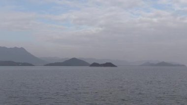 Şafak vakti sakin bir gölde sakin anlar uzak dağların üzerinden yumuşak ışığı ve sisi yakalıyor.