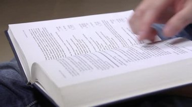 Samimi bir ortamda deri kaplı bir kitabın sayfaları aracılığıyla bilgiyi araştırıyor.