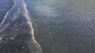 Gün batımında dingin göl kenarında büyüleyici su dalgalanmaları.