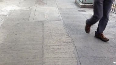 Parlak güneş ışığı altında hareketli bir şehir caddesinde zıt kaldırım tasarımlarıyla kentsel dönüşümü keşfeden