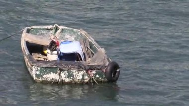 Güneşli bir nehirde çalışan balıkçı ağları ustalıkla onarırken teknesi su yüzeyinde yavaşça sallanıyor.