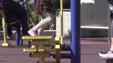 Güneşli bir parkta renkli çocuk parkı ekipmanlarıyla oynayan çocukların neşeli anları