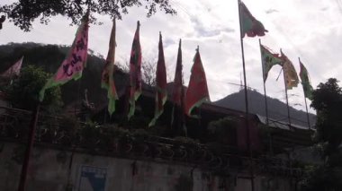 Büyüleyici bir köyde canlı bir kutlama sırasında bulutlu bir gökyüzünün altında rüzgarda dans eden renkli bayraklar.