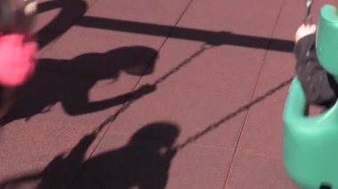 Güneşli bir öğleden sonra, parkta gölgelerin içinde sallanan neşe