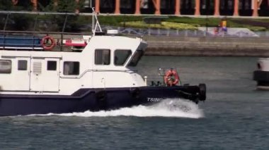 Hareketli bir limanda güneşli bir gökyüzünün altında sakin sularda süzülen römorkör.