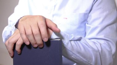 Kapalı bir ortamda, bir kitabın üzerinde dinlenen dikkatli eller.