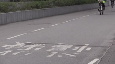 Canlı işaretler ve güneşli bir öğleden sonra temiz havayla dolu şehir yollarında gezinen bisikletçiler.